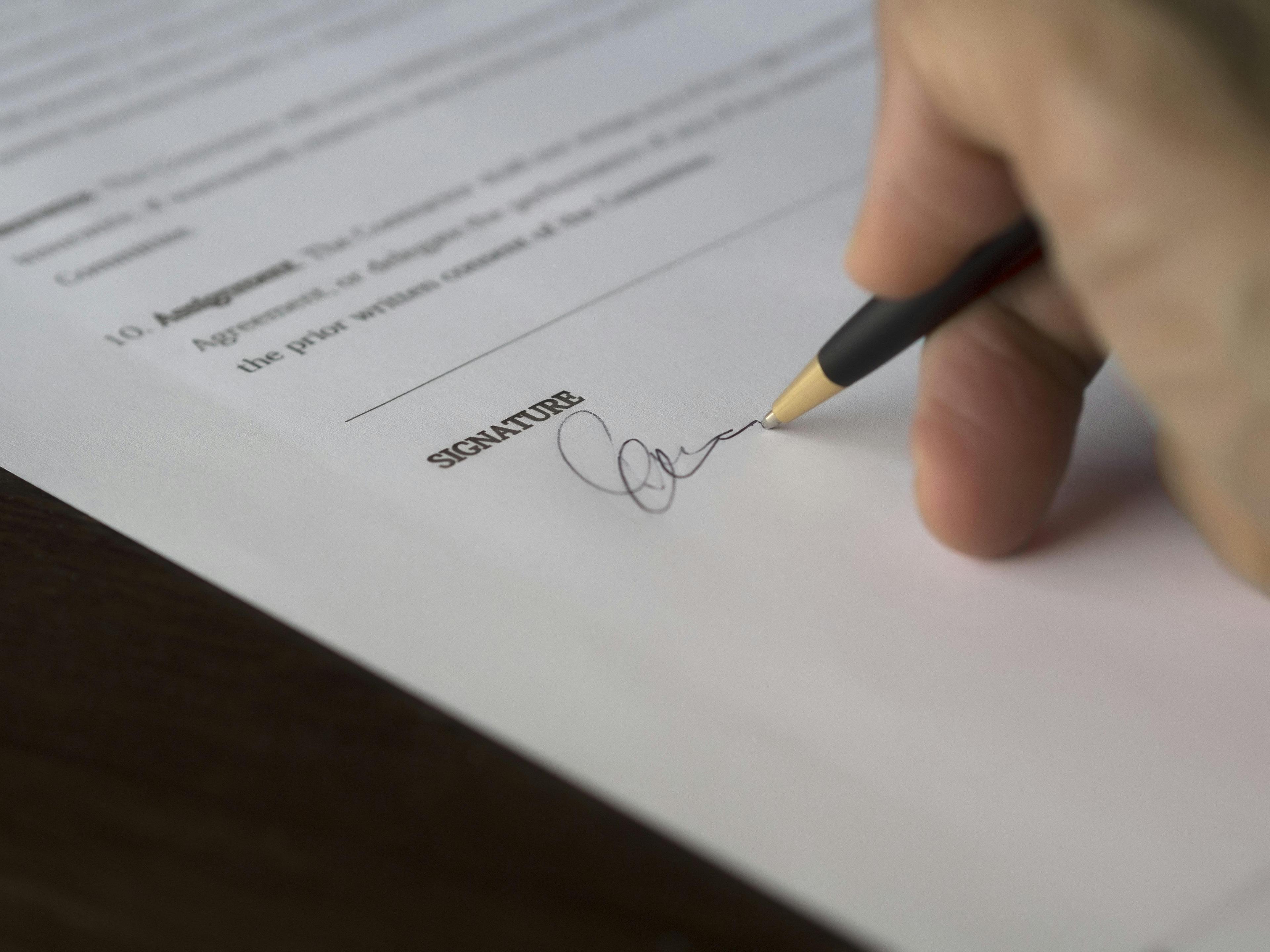Mano firmando un documento.